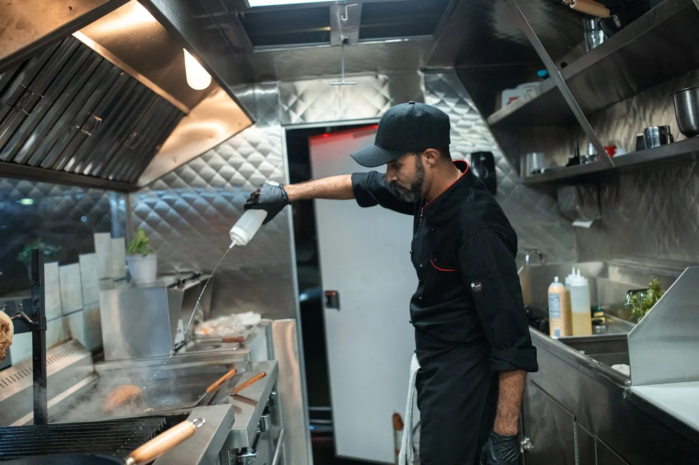 Stock photo of a cook working under a stainless exhaust hood with baffle filters
