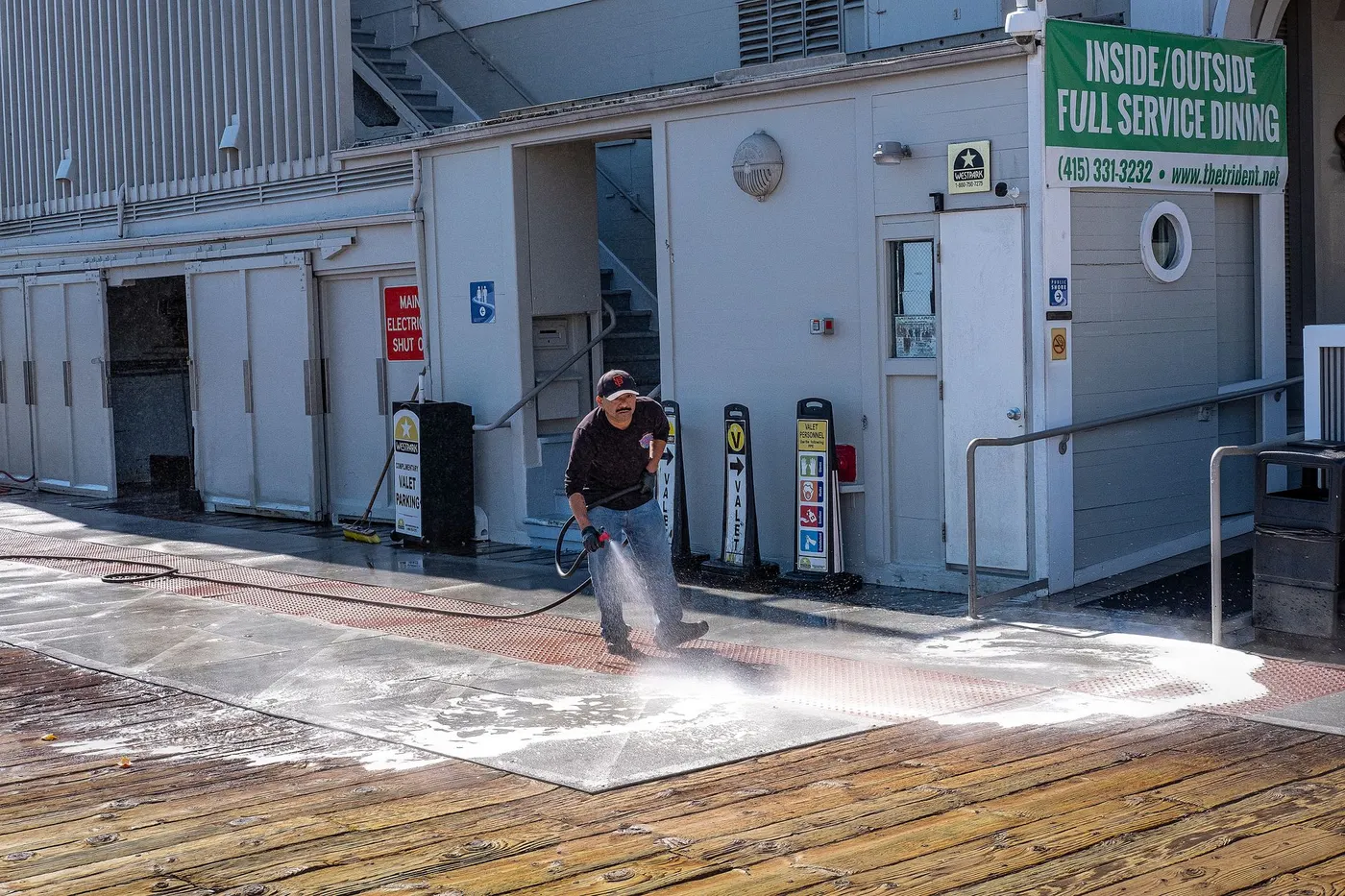 Stock photo of a worker pressure washing the walkway outside a restaurant